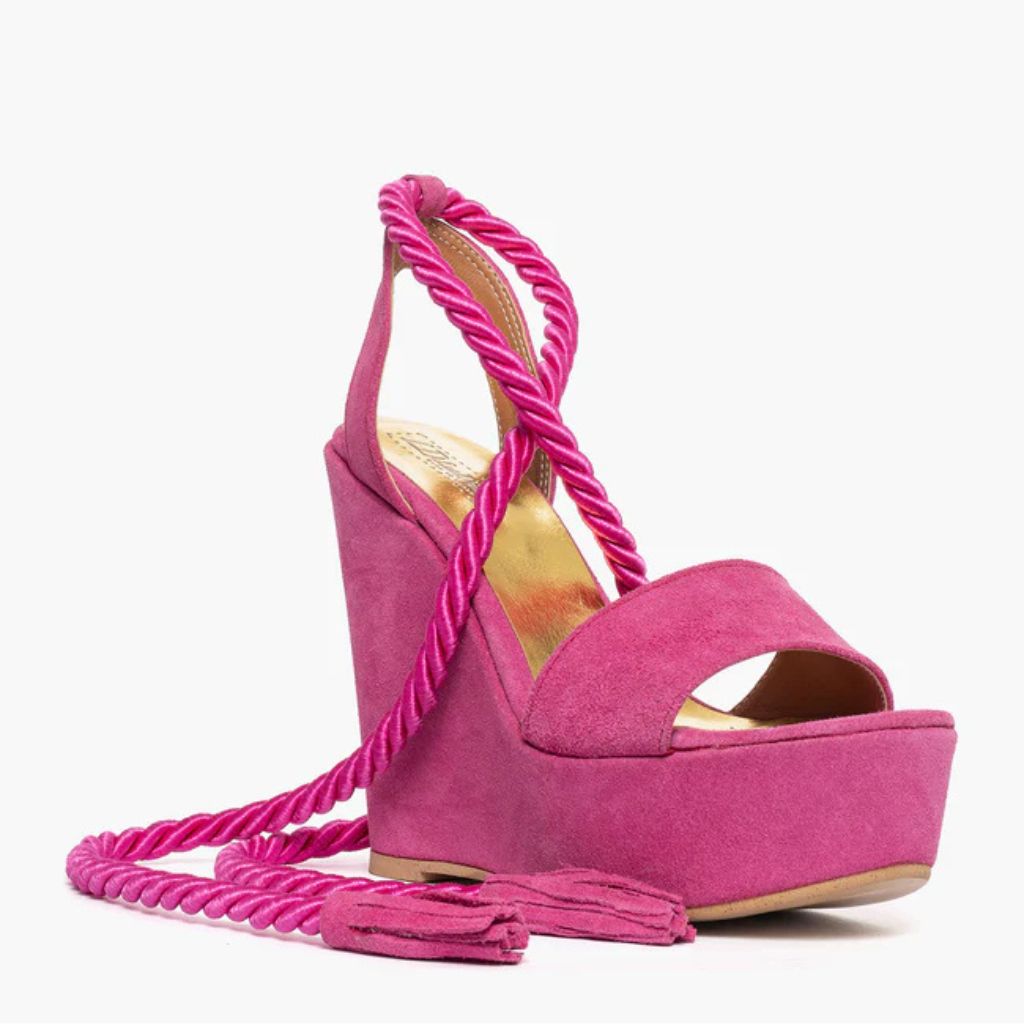 Sandalo con zeppa alta 11 cm in camoscio fucsia e lacci a corda intrecciati alla caviglia.