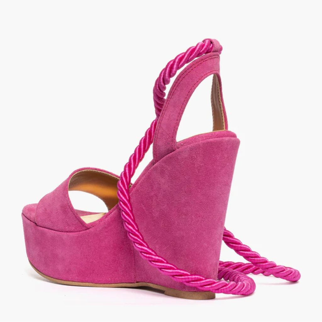 Sandalo con zeppa alta 11 cm in camoscio fucsia e lacci a corda intrecciati alla caviglia.