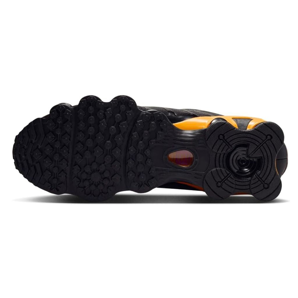 Vista laterale delle Nike Shox TL nere con colonne ammortizzanti gialle e dettagli argento metallizzato, tomaia in mesh con gabbia sintetica lucida.