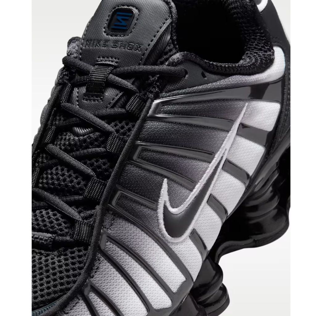 Sneaker Nike Shox TL con tomaia sfumata dal nero all'Off Noir, gabbia esterna sagomata e suola con colonne ammortizzanti integrali su fondo bianco.