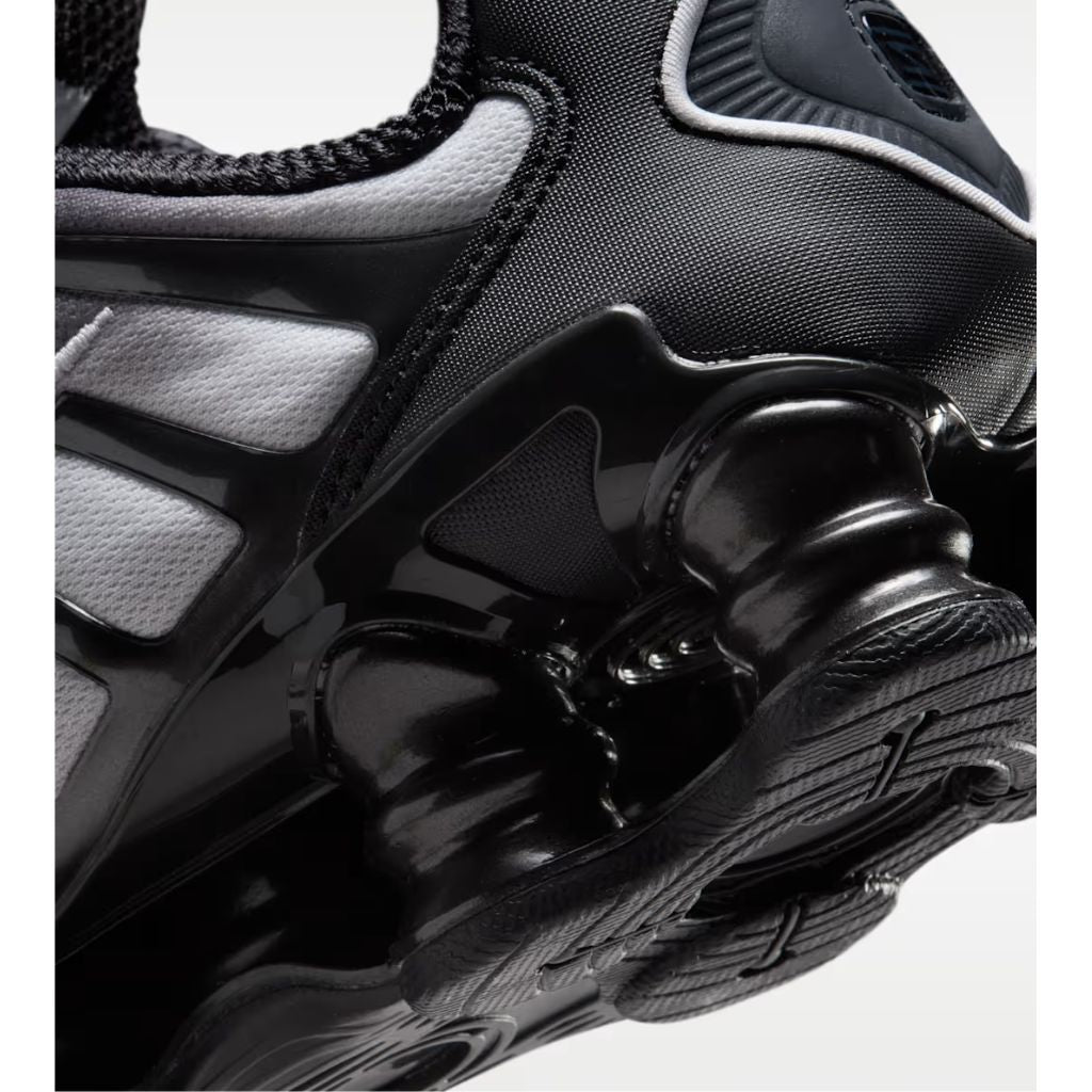 Sneaker Nike Shox TL con tomaia sfumata dal nero all'Off Noir, gabbia esterna sagomata e suola con colonne ammortizzanti integrali su fondo bianco.