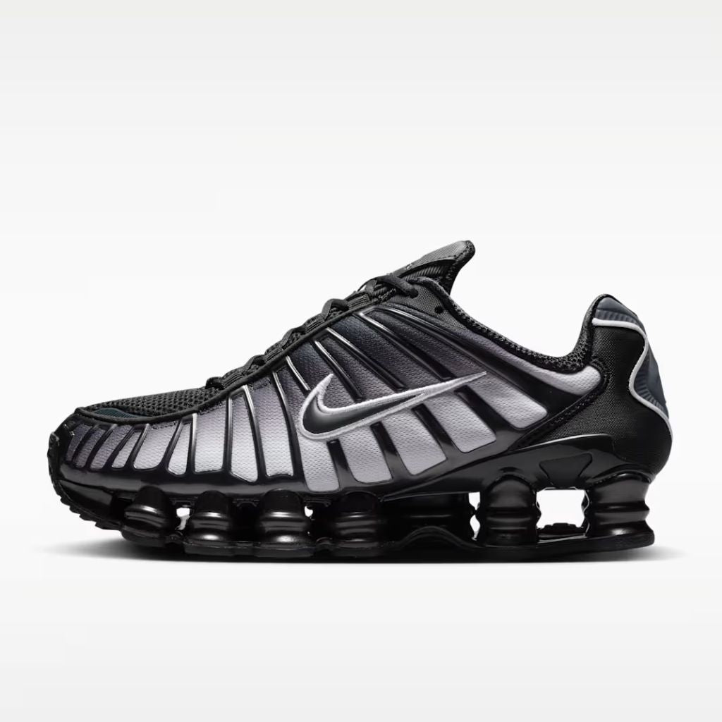 Sneaker Nike Shox TL con tomaia sfumata dal nero all'Off Noir, gabbia esterna sagomata e suola con colonne ammortizzanti integrali su fondo bianco.