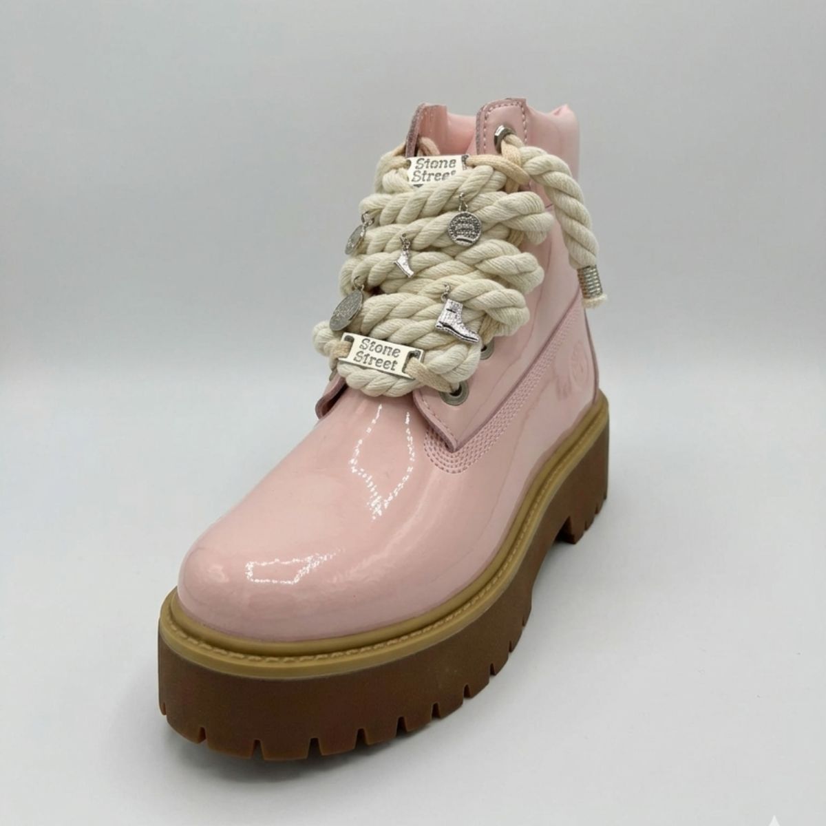 Stivale Timberland Platform Stone Street in vernice rosa cipria con lacci a corda, charm in metallo argento e suola platform