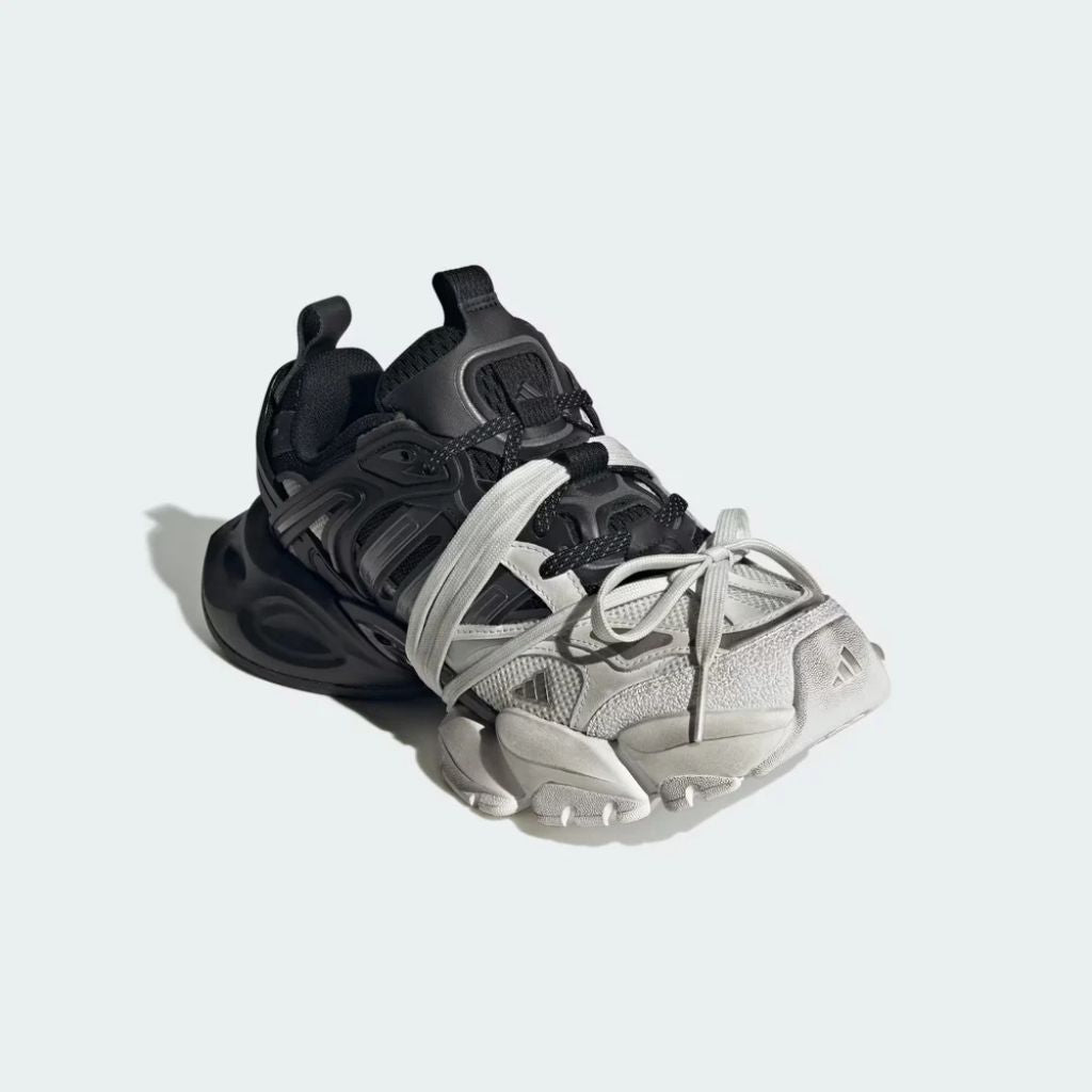 Sneaker Adidas XLG Runner Deluxe in bianco e nero con design ispirato agli anni 200, tomaia stratificata in tessuto e pelle, e suola spessa in gomma.