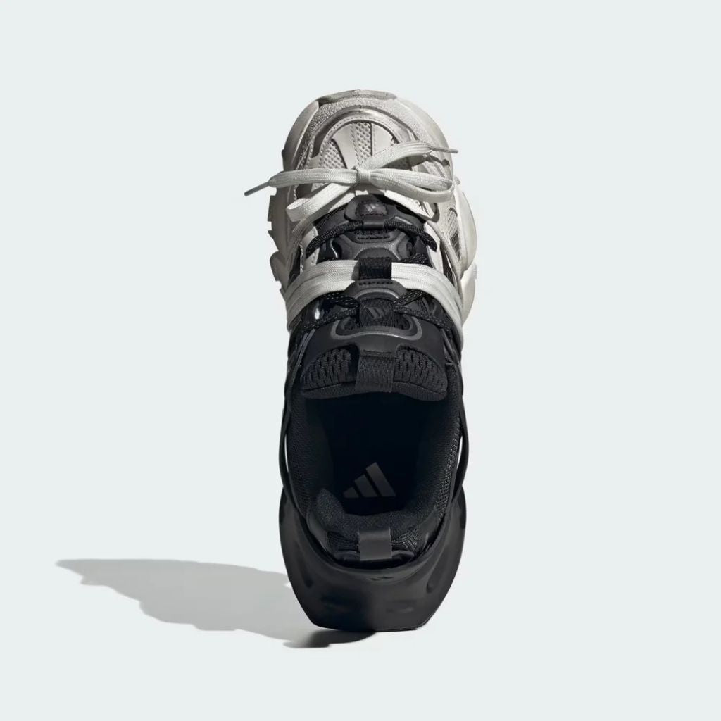 Sneaker Adidas XLG Runner Deluxe in bianco e nero con design ispirato agli anni 200, tomaia stratificata in tessuto e pelle, e suola spessa in gomma.
