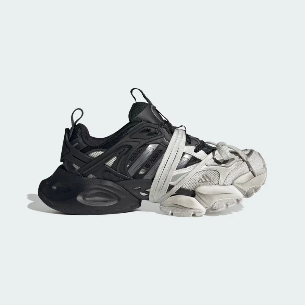 Sneaker Adidas XLG Runner Deluxe in bianco e nero con design ispirato agli anni 200, tomaia stratificata in tessuto e pelle, e suola spessa in gomma.