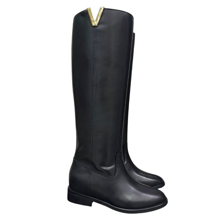 Stivale al ginocchio in pelle nera con rialzo interno 8 cm, accessorio oro e punta tonda.