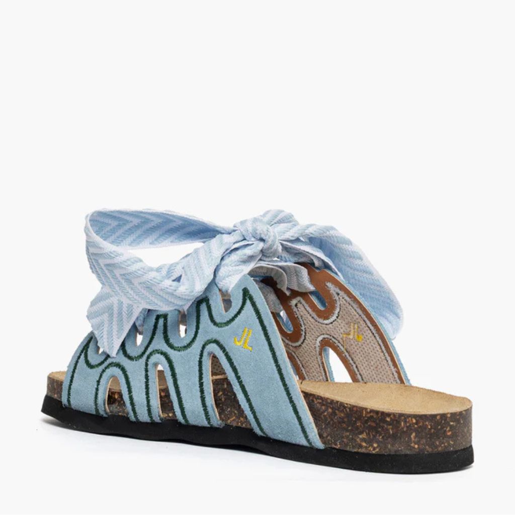 Ciabatta in camoscio celeste Jammers London con ricami verdi e grande laccio azzurro annodato.