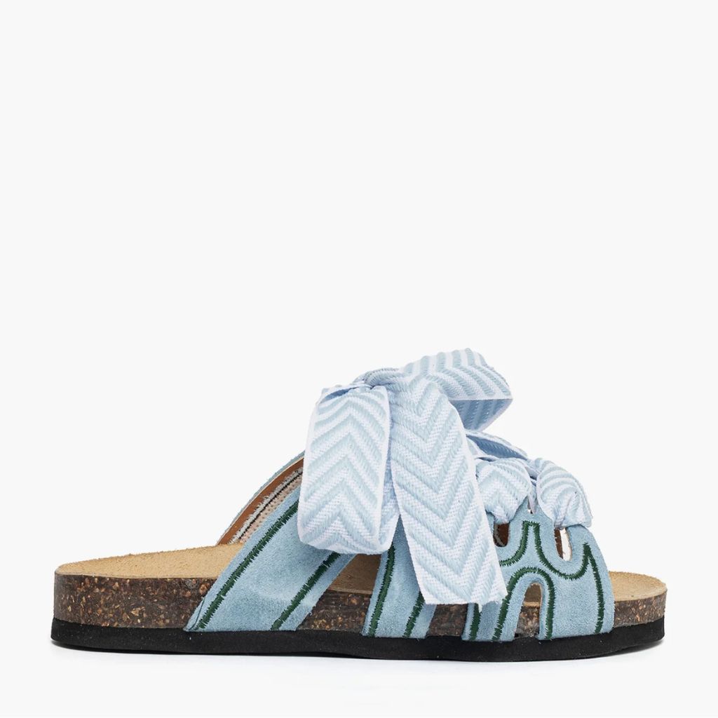 Ciabatta in camoscio celeste Jammers London con ricami verdi e grande laccio azzurro annodato.