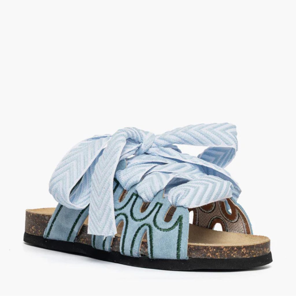 Ciabatta in camoscio celeste Jammers London con ricami verdi e grande laccio azzurro annodato.