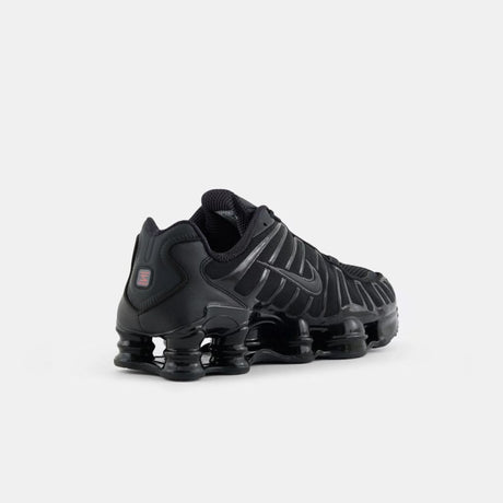 Vista laterale delle sneaker Nike Shox TL nella colorazione Black Metallic Hematite, con l'iconica suola a colonne e dettagli neri lucidi su tomaia in mesh.
