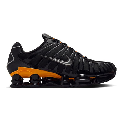 Vista laterale delle Nike Shox TL nere con colonne ammortizzanti gialle e dettagli argento metallizzato, tomaia in mesh con gabbia sintetica lucida.