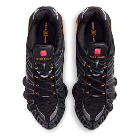 Vista laterale delle Nike Shox TL nere con colonne ammortizzanti gialle e dettagli argento metallizzato, tomaia in mesh con gabbia sintetica lucida.