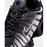 Sneaker Nike Shox TL con tomaia sfumata dal nero all'Off Noir, gabbia esterna sagomata e suola con colonne ammortizzanti integrali su fondo bianco.