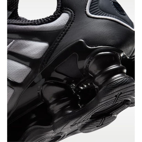 Sneaker Nike Shox TL con tomaia sfumata dal nero all'Off Noir, gabbia esterna sagomata e suola con colonne ammortizzanti integrali su fondo bianco.