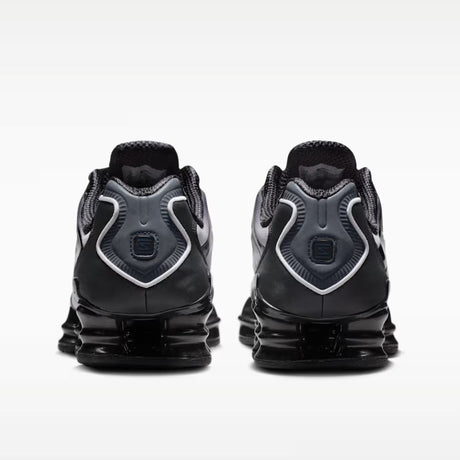 Sneaker Nike Shox TL con tomaia sfumata dal nero all'Off Noir, gabbia esterna sagomata e suola con colonne ammortizzanti integrali su fondo bianco.