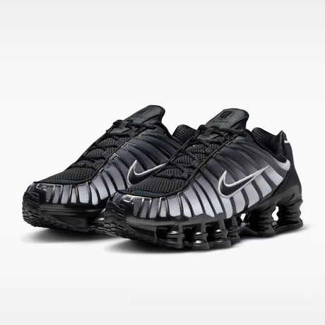 Sneaker Nike Shox TL con tomaia sfumata dal nero all'Off Noir, gabbia esterna sagomata e suola con colonne ammortizzanti integrali su fondo bianco.