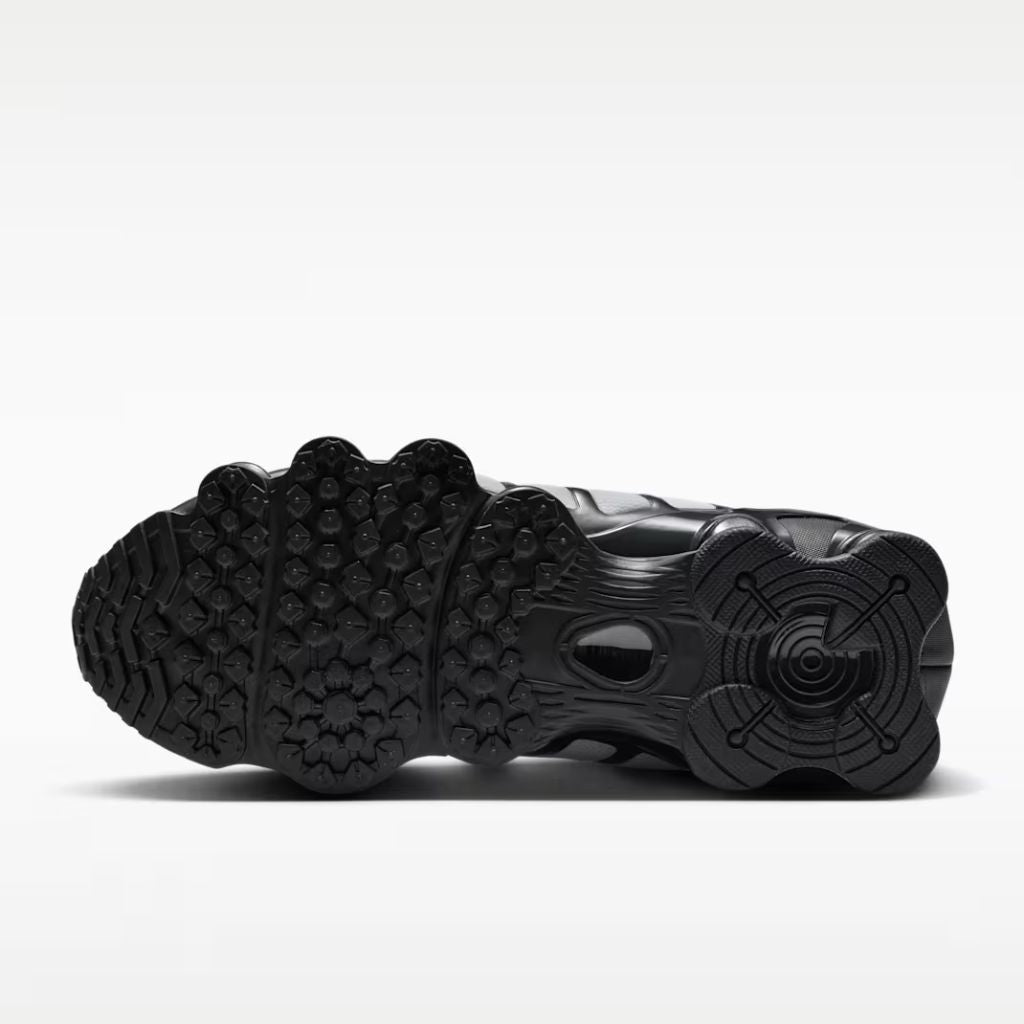 Sneaker Nike Shox TL con tomaia sfumata dal nero all'Off Noir, gabbia esterna sagomata e suola con colonne ammortizzanti integrali su fondo bianco.