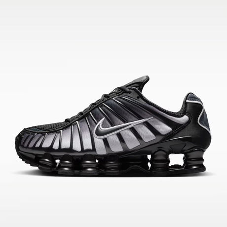 Sneaker Nike Shox TL con tomaia sfumata dal nero all'Off Noir, gabbia esterna sagomata e suola con colonne ammortizzanti integrali su fondo bianco.