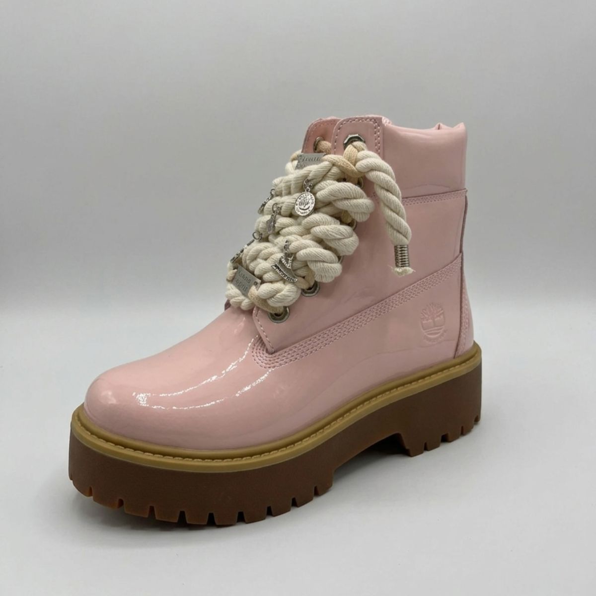 Stivale Timberland Platform Stone Street in vernice rosa cipria con lacci a corda, charm in metallo argento e suola platform