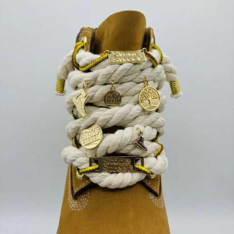 Stivale robusto in nabuk color giallo ocra, con allacciatura artistica a corda beige spessa decorata con charm placcati in oro.