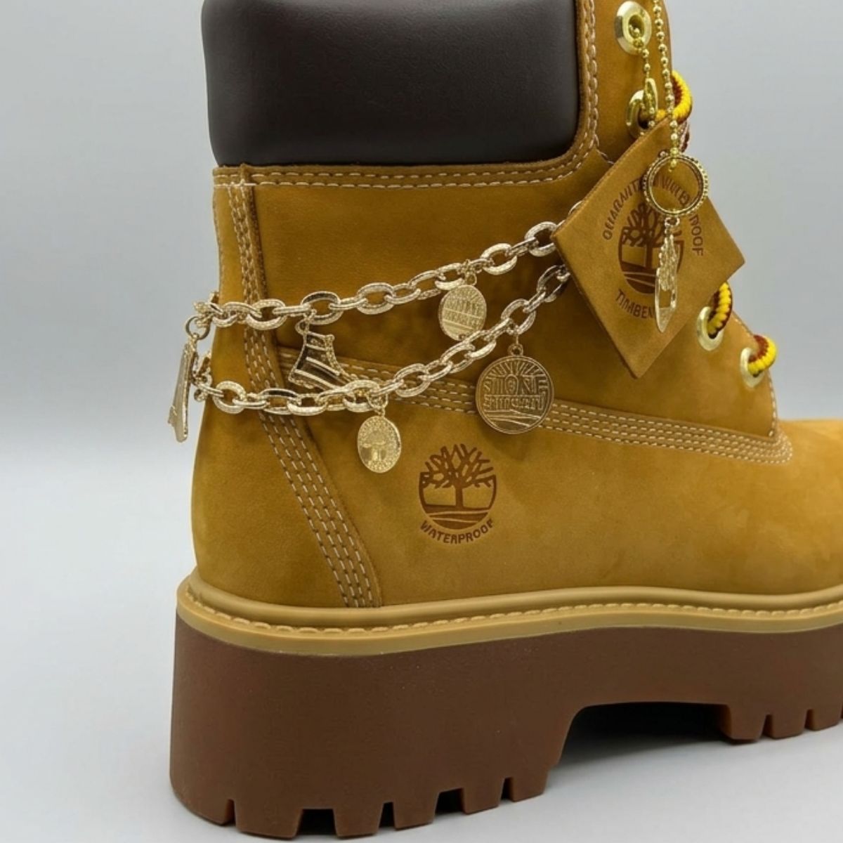 Stivale Timberland Platform Stone Street in nabuk giallo grano con catena dorata decorativa, charm e suola chunky marrone