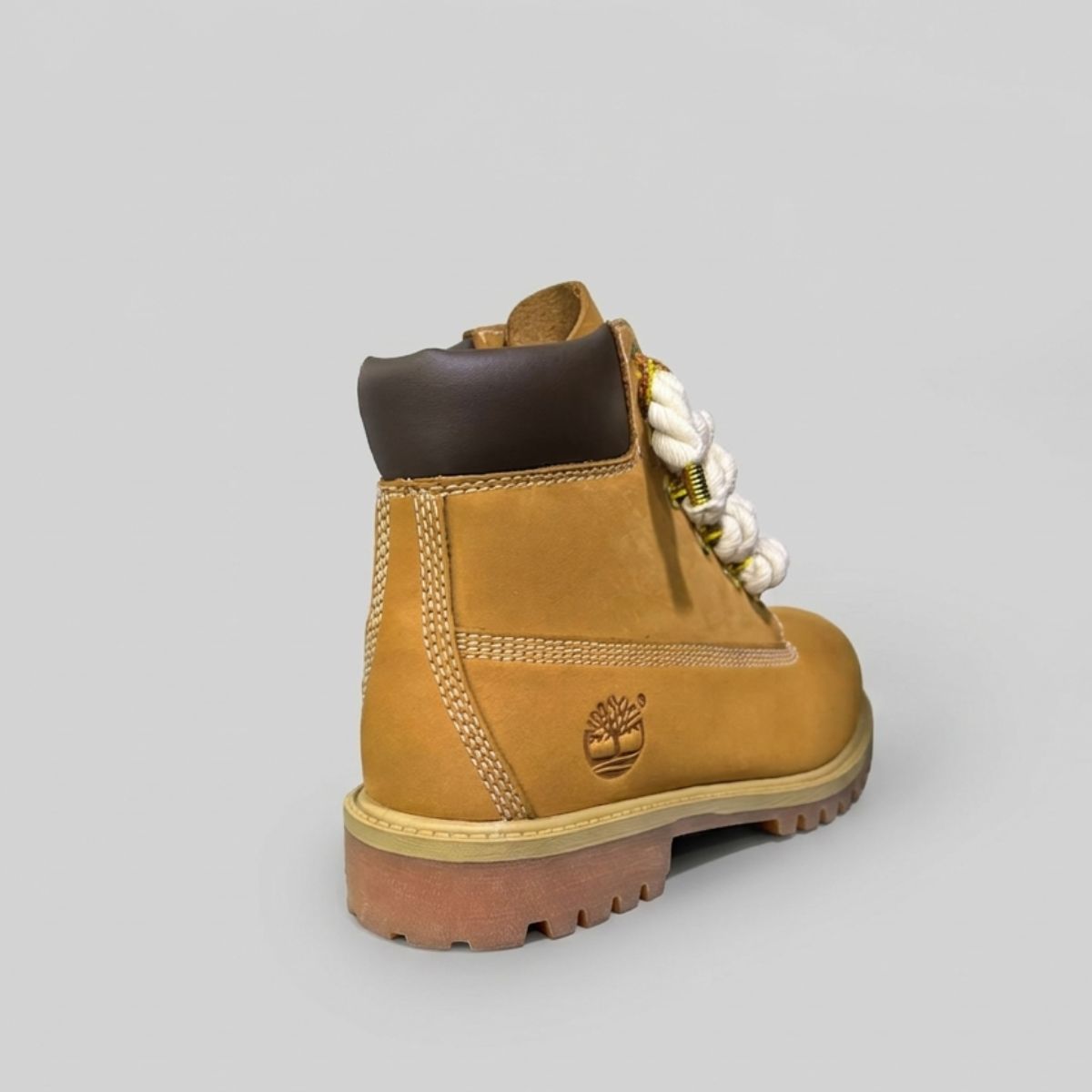 Stivale robusto in nabuk color giallo ocra, con allacciatura artistica a corda beige spessa decorata con charm placcati in oro.